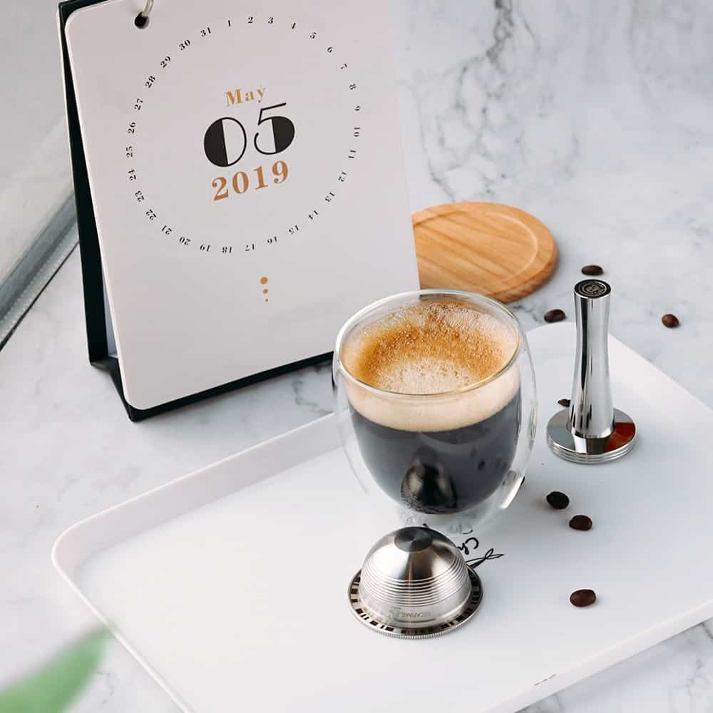 Reusable Nespresso Vertuo coffee pod along with tamper and the coffee it extracted